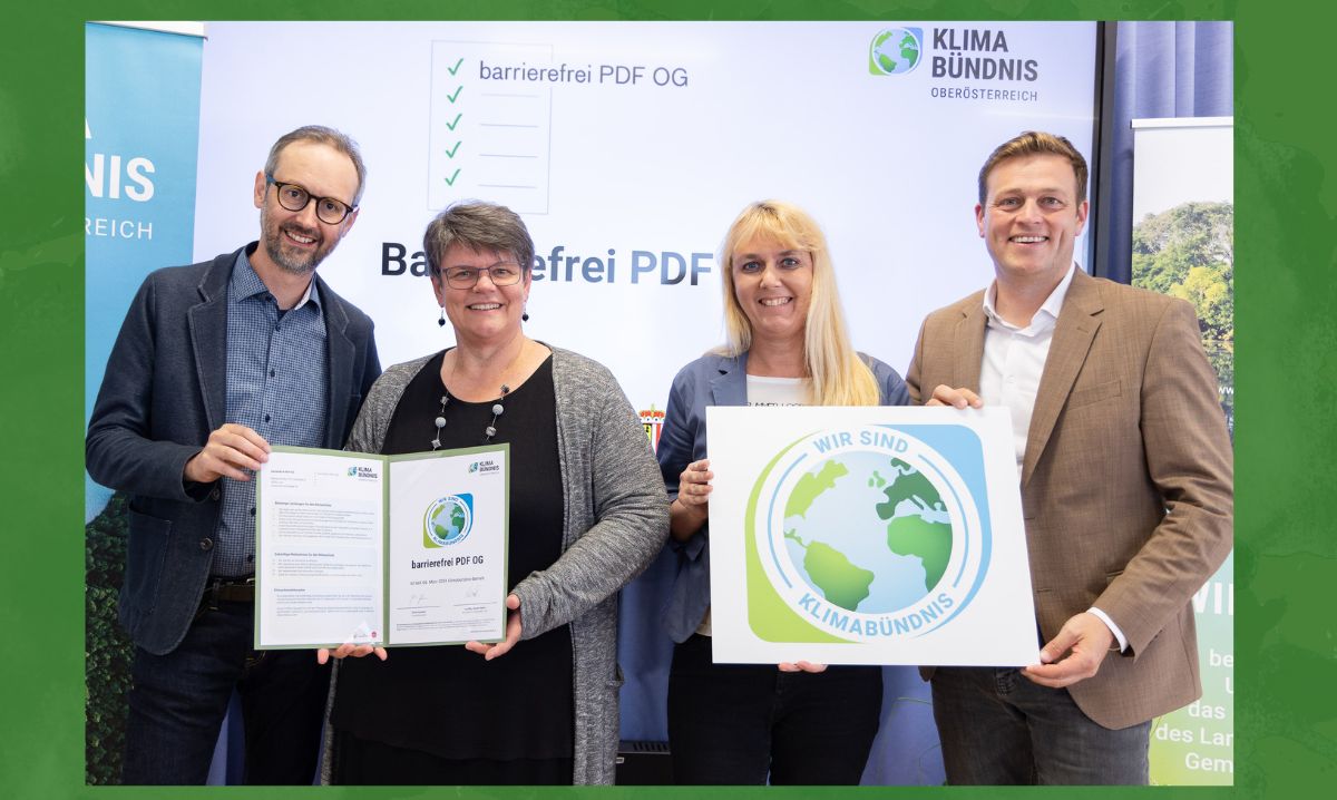 vor der Leinwand mit dem Text “Barrierefrei PDF OG” und “Klimabündnis Oberösterreich” stehen die 4 Personen